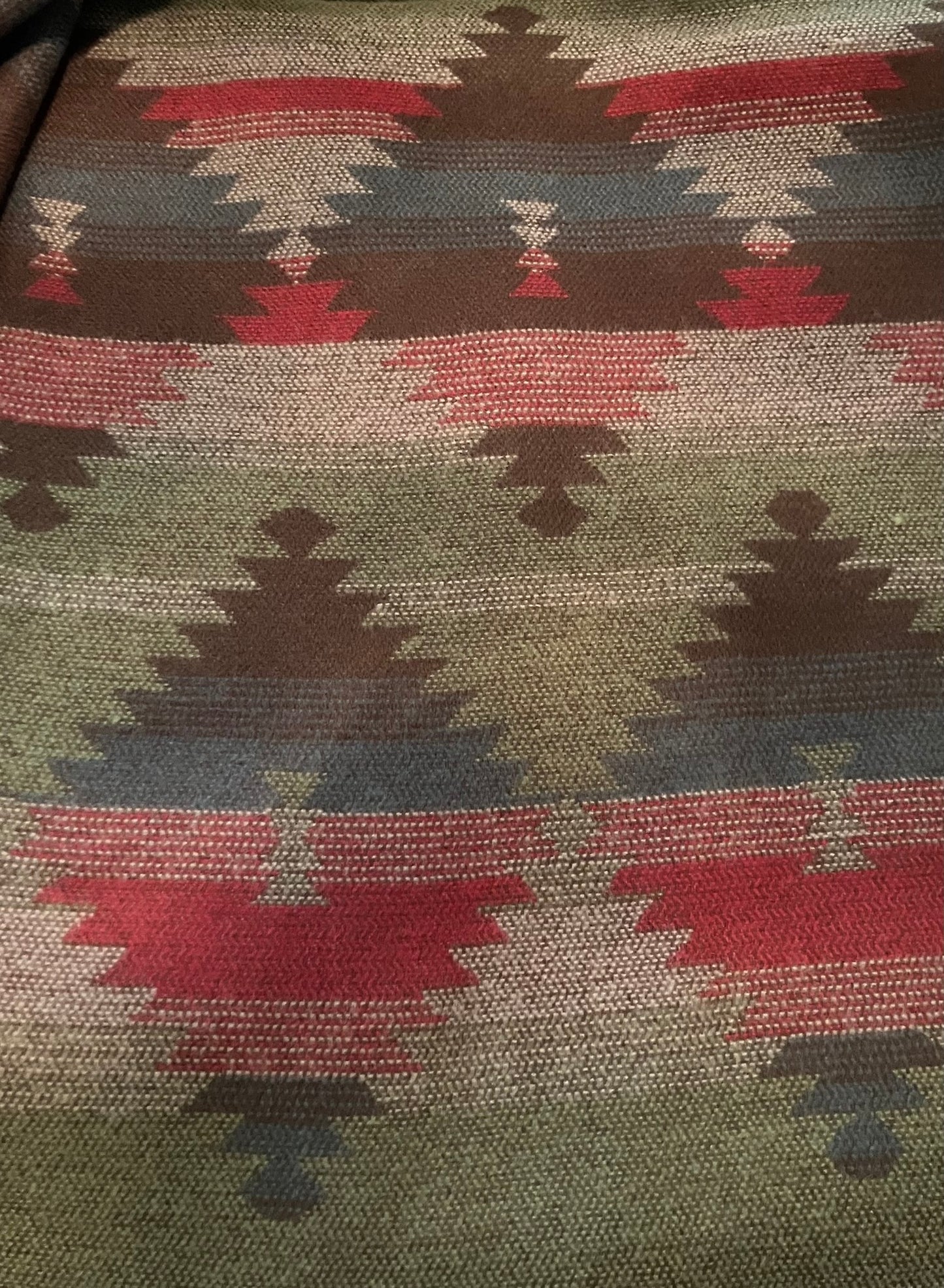 Close-up of a fabric with a geometric pattern featuring red, brown, and green colors.