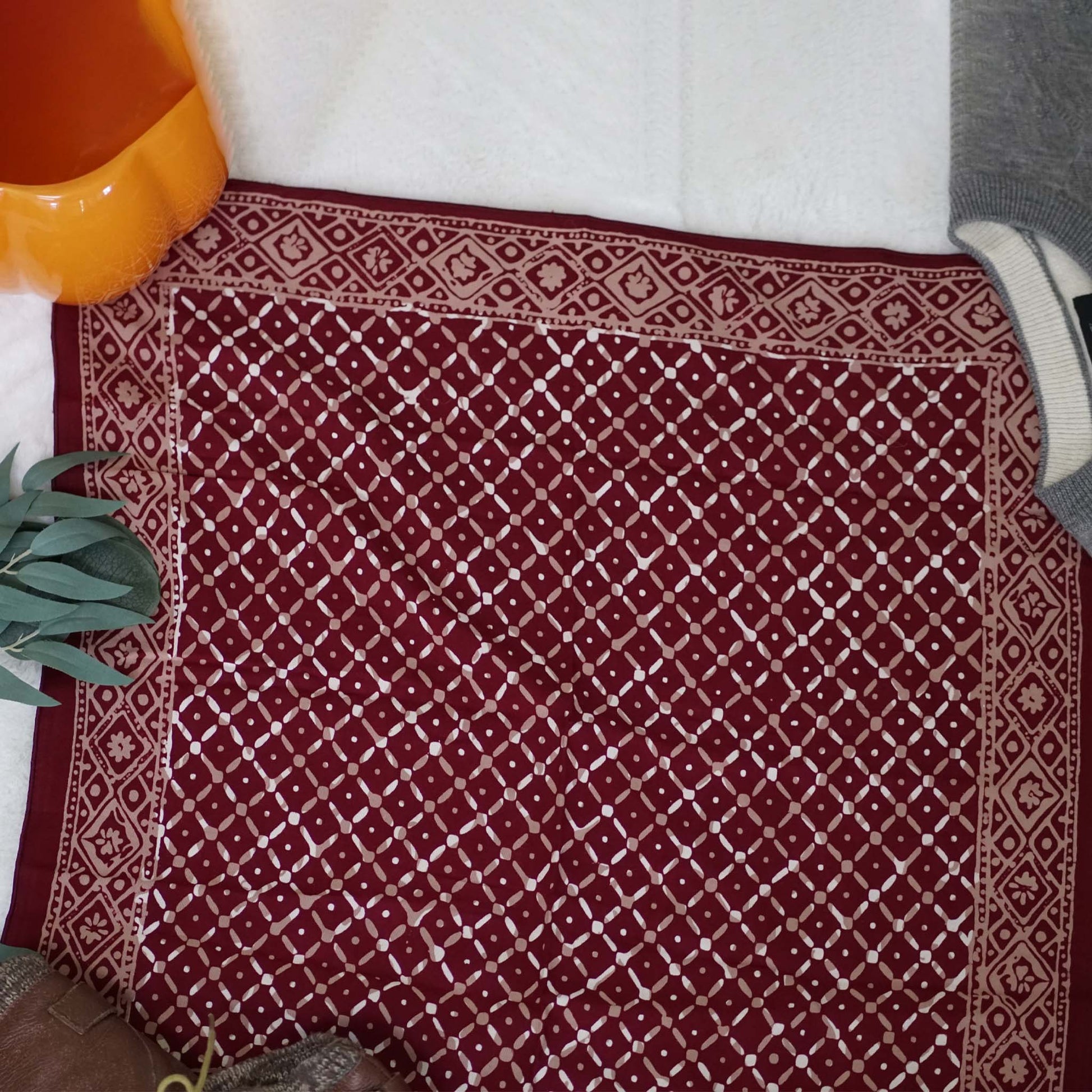 Red patterned rug with a white border on a floor.