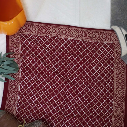 Red patterned rug with a white border on a floor.