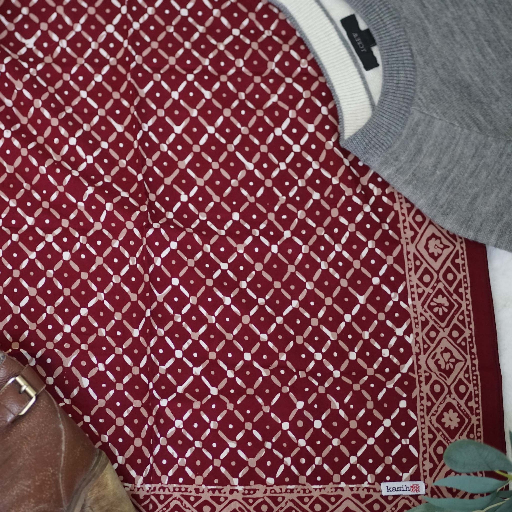 Red patterned fabric with a gray sweater and white shirt underneath