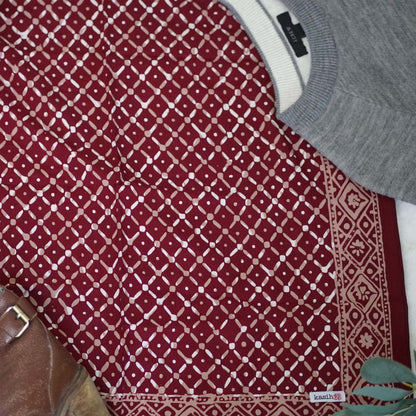 Red patterned fabric with a gray sweater and white shirt underneath