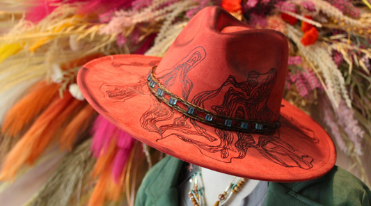 Red cowboy hat with intricate designs on a colorful background
