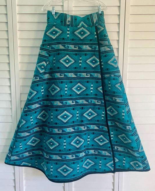 Teal patterned skirt hanging against a white wooden panel background