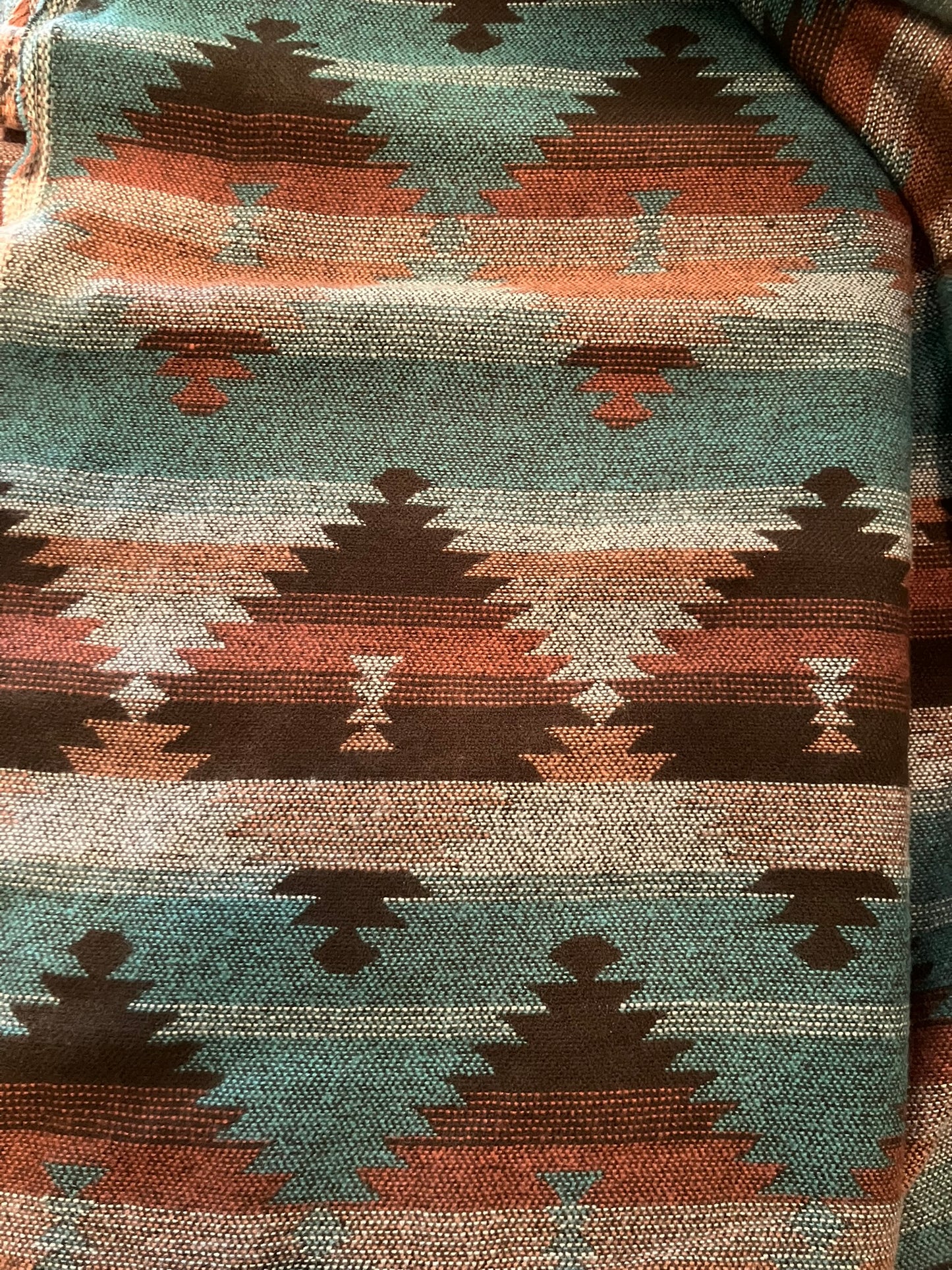 Close-up of a fabric with a geometric pattern featuring triangles and diamonds in earthy tones.