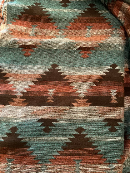 Close-up of a fabric with a geometric pattern featuring triangles and diamonds in earthy tones.