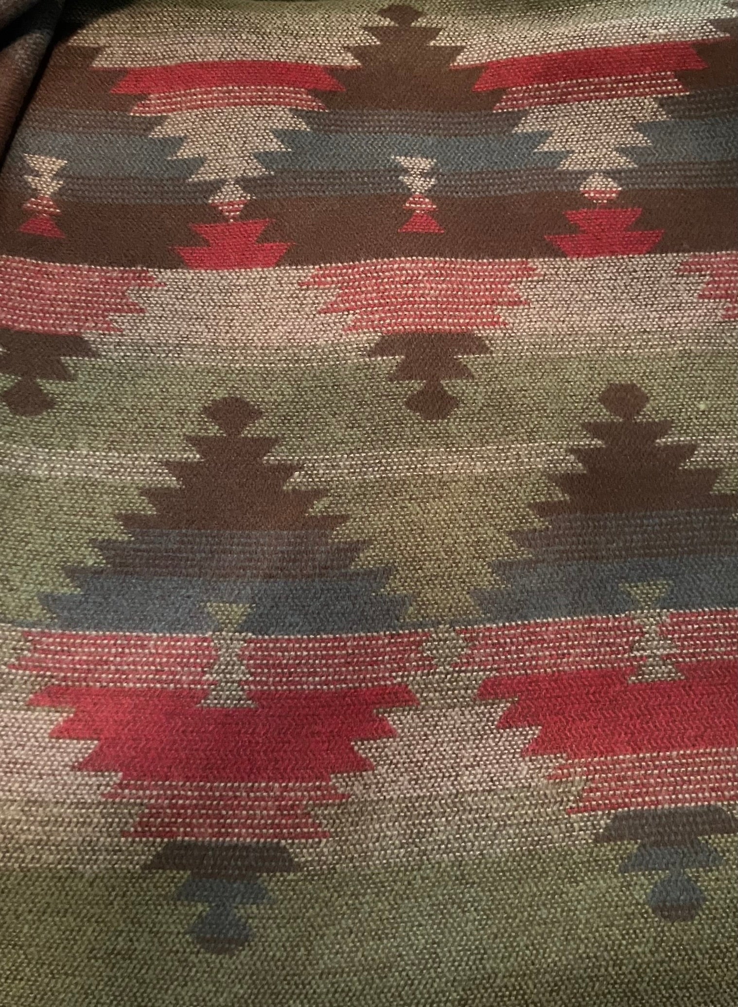Close-up of a fabric with a geometric pattern featuring red, brown, and green colors.